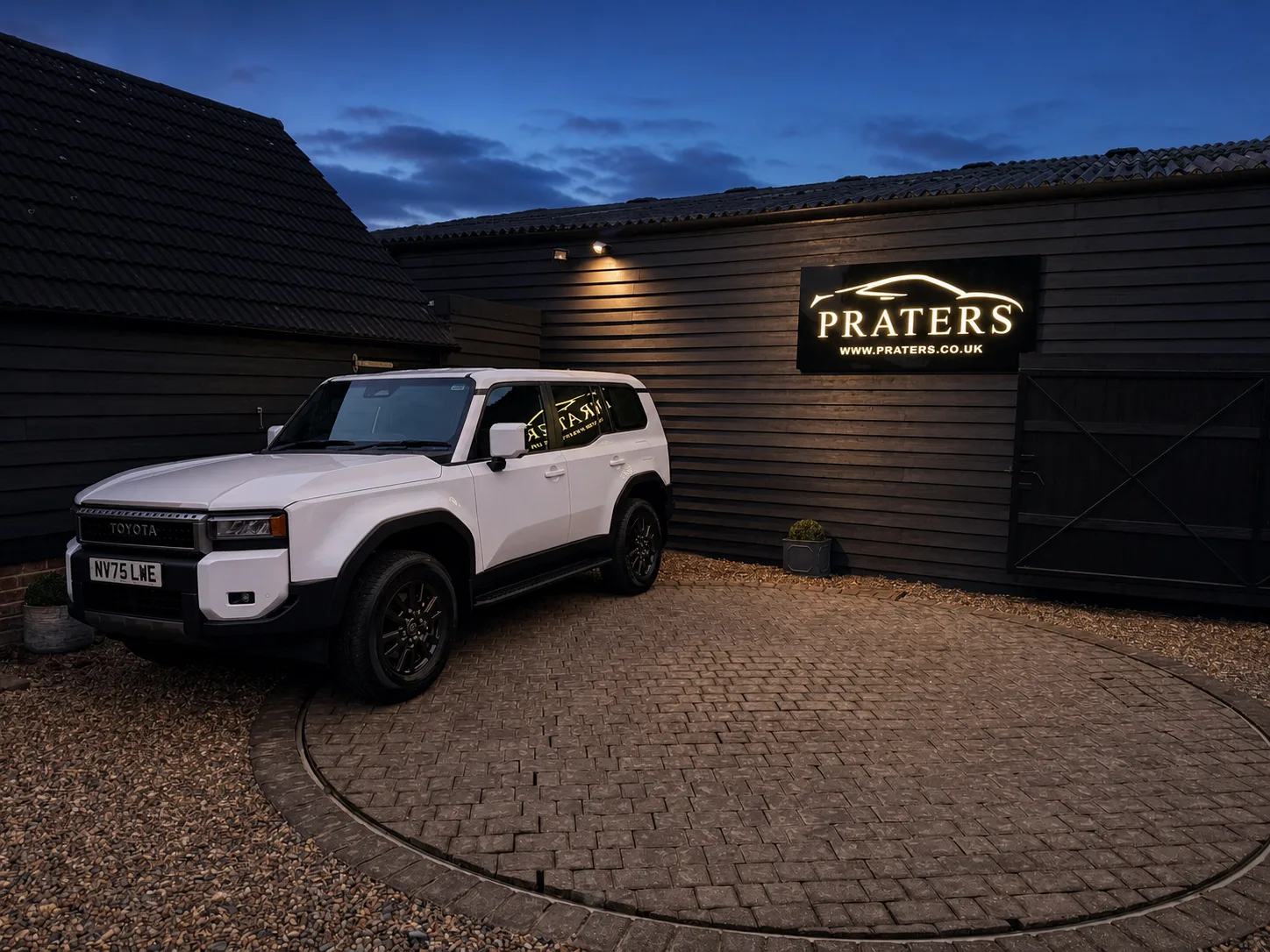 Illuminated Praters exterior sign on a dark-clad building