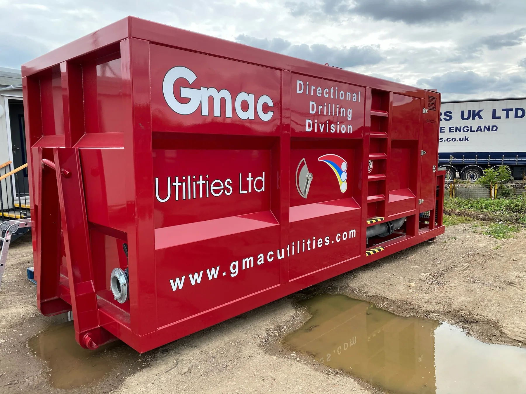 Red GMAC Utilities directional drilling unit with white cut lettering and branding