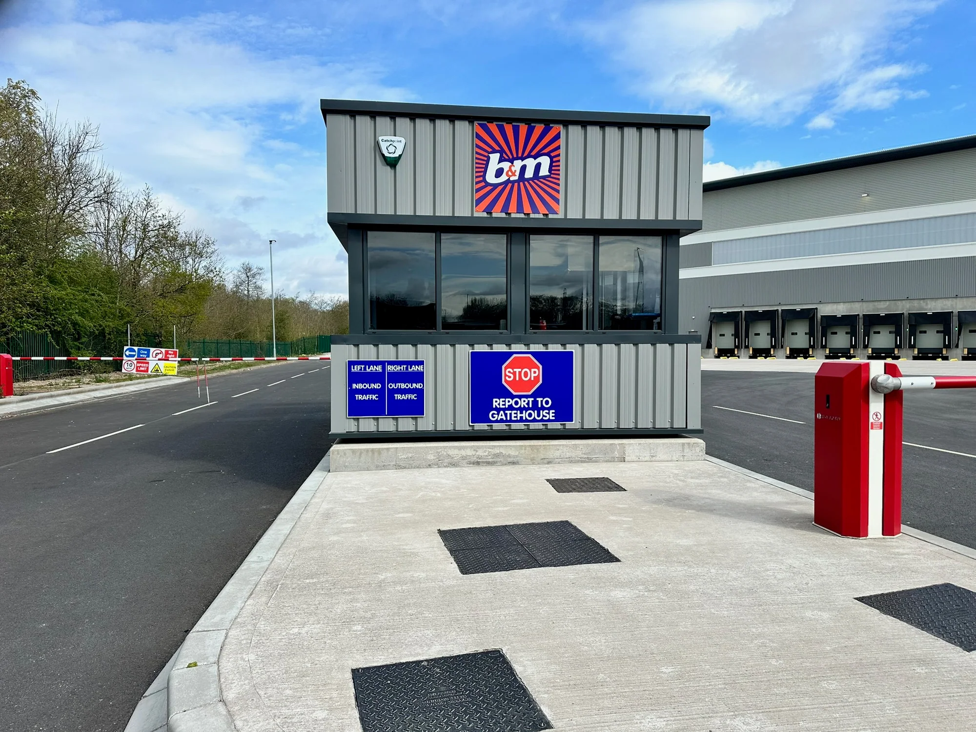 B and M distribution gatehouse with brand panel, stop instruction and lane signs