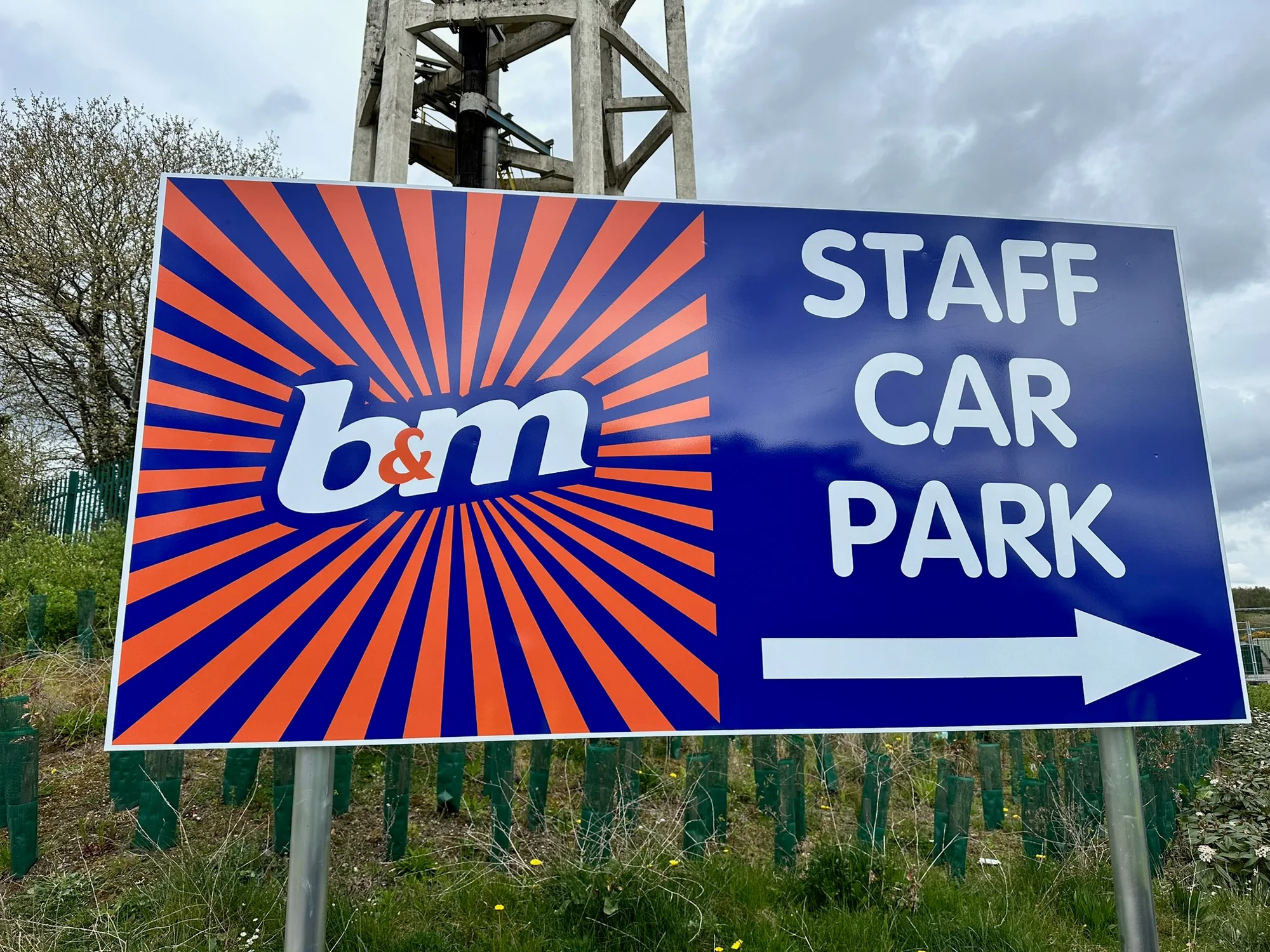 B and M staff car park directional sign beside a distribution site road