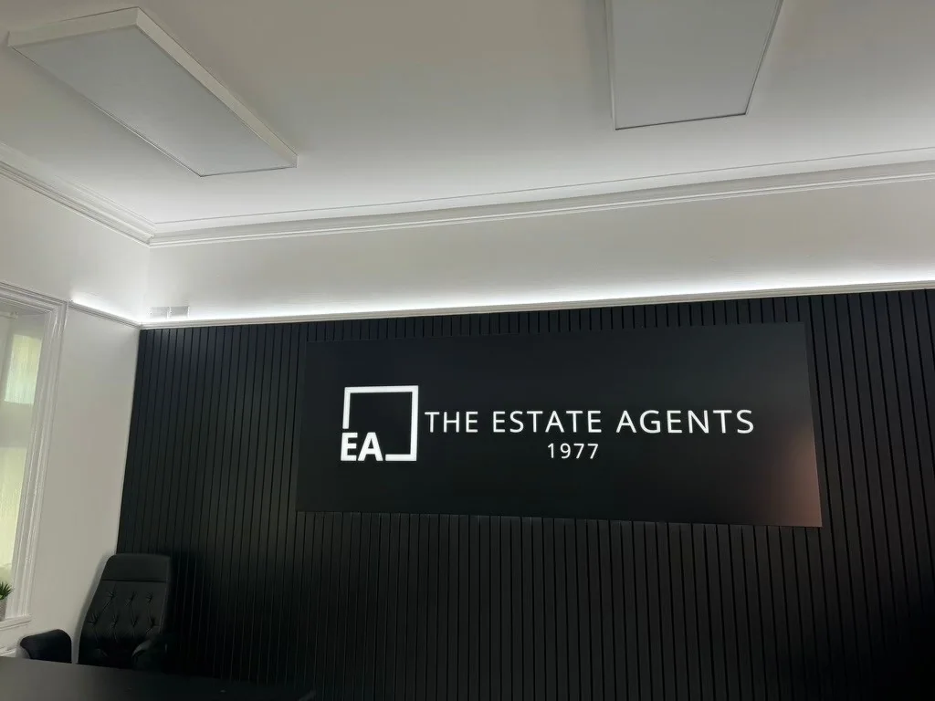 Angled view of The Estate Agents sign on a black slatted reception wall